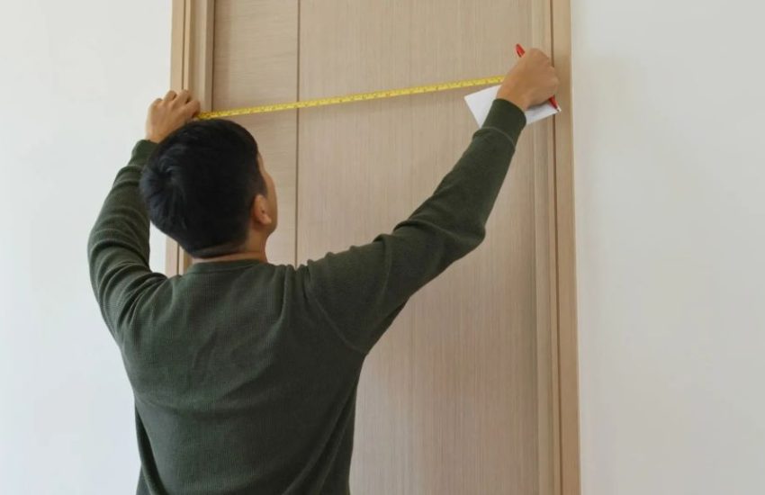 Person measuring a doorway with a tape measure to install bifold doors step by step