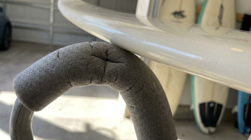 Close up of thick black foam padding protecting a surfboard rail from scratches.
