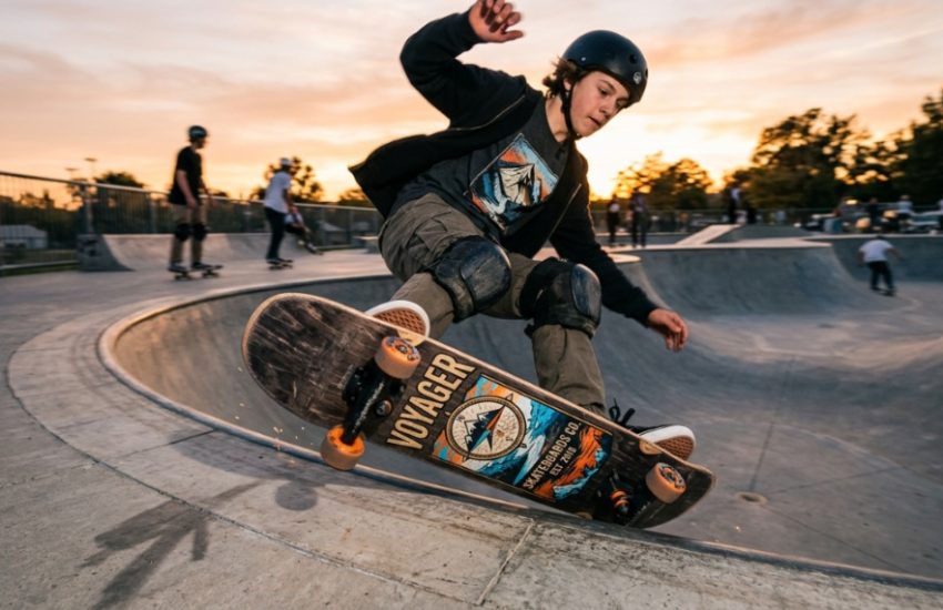 A teenager performing a kickflip on a durable Voyager skateboard outdoors.